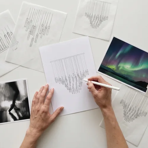 Hands sketching a chandelier beside reference images
